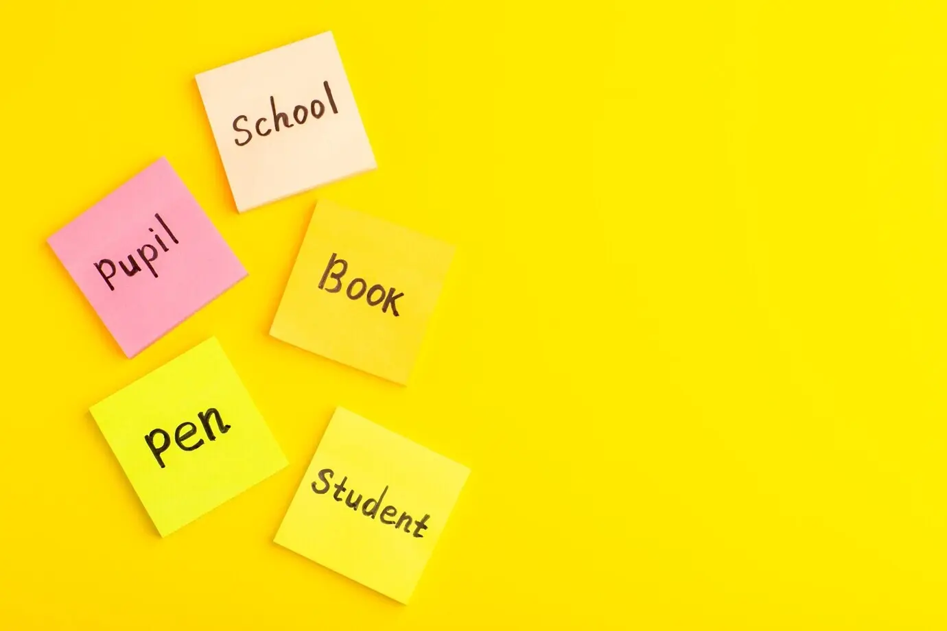 Draufsicht auf verschiedene Aufkleber mit Wörtern darauf, die auf einer gelben Oberfläche verteilt sind.